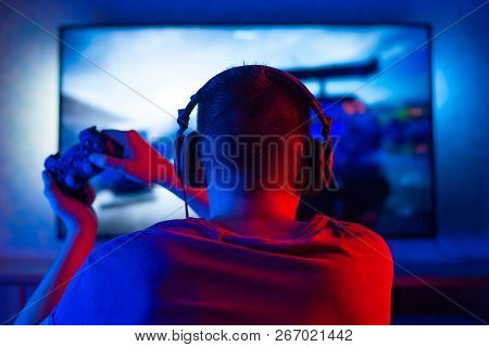 Rear View Of A Young Player Playing Video Games On An Fps Console At Home