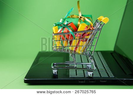 Ciber Monday Concept - Trolley Cart With Christmas Presents On Notebook, Green Background