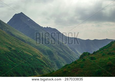 Blurred Rainy Landscape In The Caucasus, Overcast Sky, Mountain Peaks And Green Slopes
