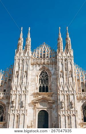 Main Entrance With Spiers And Statues Of The Milan Cathedral And Blue Sky