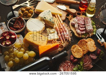 Huge assortment of various tasety spanish, french or italian apertizers. Cheese, meat, olives, stuffed peppers, bread, sticks. Placed on rusty dark background. View from above.