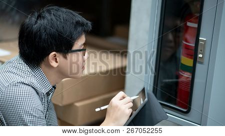 Young Asian Male Technician Checking Red Fire Extinguisher In Fire Hose Cabinet (fhc) By Using Digit