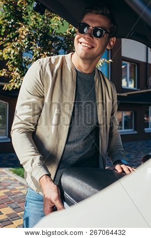 Smiling Man Putting Baggage Into Car, Travel Concept