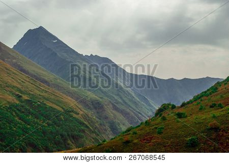 Blurred Rainy Landscape In The Caucasus, Overcast Sky, Mountain Peaks And Green Slopes