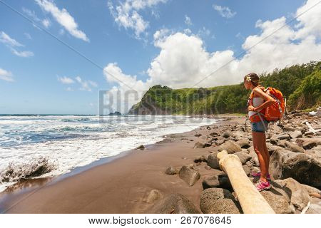 Travel tourist woman in Hawaii beach USA vacation on Pololu Valley hike to beach looking at ocean landscape mountains background. Big Island, Hawaii. Girl hiking with backpack in summer holidays.