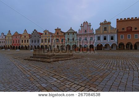 Scenic Morning View Of Main Square In Medieval Telc. Fountain With Statue Of St. Margaret And Colorf