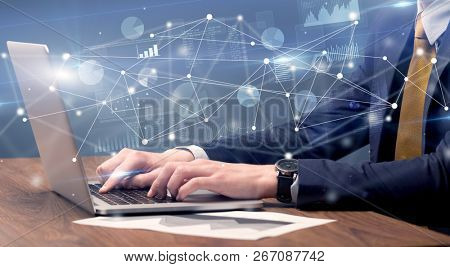 Businessman typing on laptop with linked reports charts grapghs around