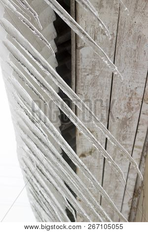 Melted Snow And Large Icicles Hanging From The Roof Of The House.