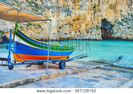 The Colored Wooden Maltese Luzzu Boat On Shore Of Dwejra Inland Sea With A View On Blue Hole Grotto 
