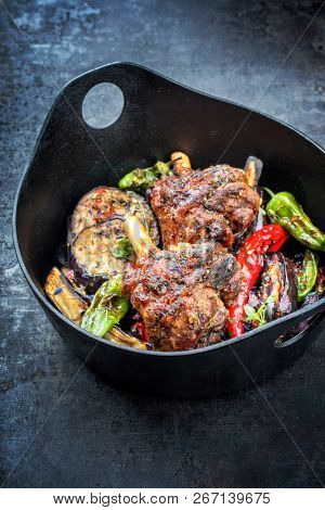 Traditional barbecue leg of lamb with eggplant and chili as top view in a modern style Japanese cast-iron roasting dish with copy space 