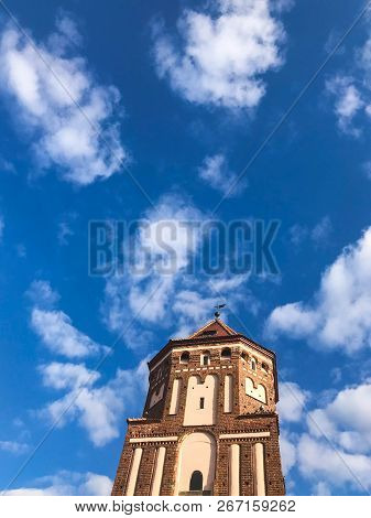 Towers And Spiers Of A High Medieval Stone Old Ancient Beautiful Castle Against A Blue Sky.