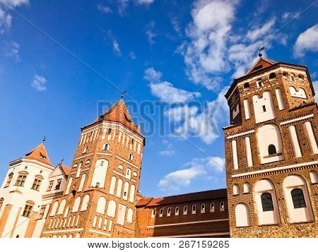 Towers And Spiers Of A High Medieval Stone Old Ancient Beautiful Castle Against A Blue Sky.
