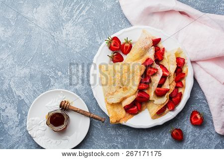 Сrepes With Fresh Strawberries And Honey On Gray Concrete Background. Top View.