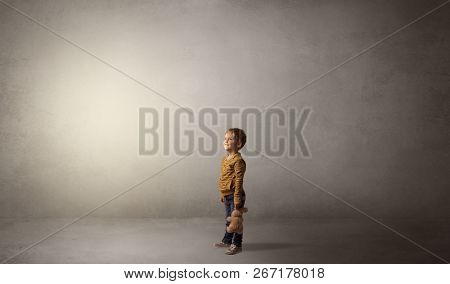 Little waggish kid staying alone in a big empty room with his plush