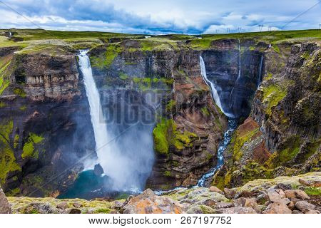 Cloudy and windy summer day in Iceland. Complex of high waterfalls of Haifoss in a dangerous tundra canyon. The concept of extreme and phototourism