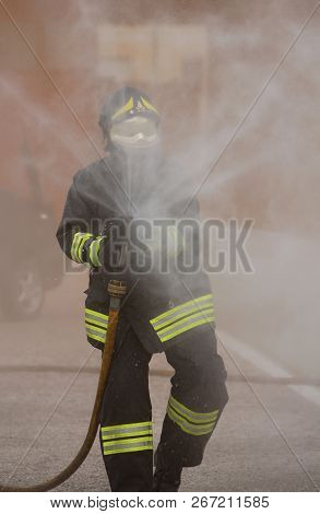 Italia, Italy - May 10, 2018: Italian Fireman With Uniform And Helmet Uses The Hydrant With Foam Dur
