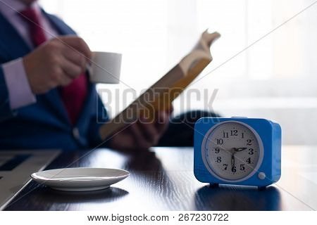 A Man In A Business Suit Reads A Book And Drinks Coffee. The Concept Of Investing In Yourself And Ge