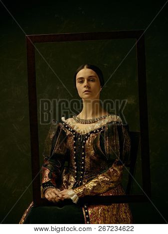 Portrait Of A Girl Wearing A Princess Or Countess Dress Over Dark Studio. Portrait Through Picture F