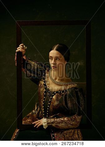 Portrait Of A Girl Wearing A Princess Or Countess Dress Over Dark Studio. Portrait Through Picture F