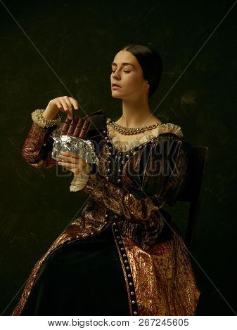 Portrait Of A Girl Wearing A Princess Or Countess Dress Over Dark Studio. Portrait With Sweet Chocol