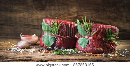 Raw beef fillet steaks mignon with spices on wooden background