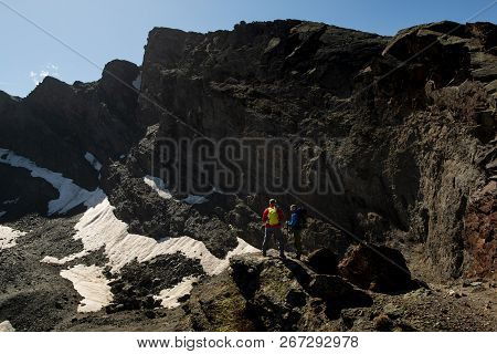 Two Anonymous Travelers Standing On Rough Rock And Admiring Picturesque View Of Majestic Mountains I