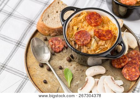Slovak Christmas National Cabbage Soup In Small Black Pot With Sausage On Old Steel Plate.