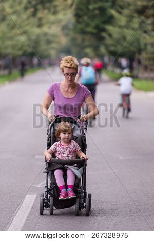 young healthy mother jogging while pushing a baby stroller at city park