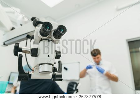 Doctor Used Microscope. Dentist Is Treating Patient In Modern Dental Office. Operation Is Carried Ou