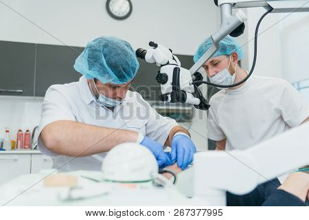 Doctor Used Microscope. Dentist Is Treating Patient In Modern Dental Office. Operation Is Carried Ou