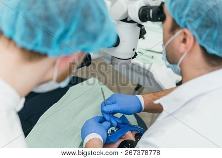 Doctor Used Microscope. Dentist Is Treating Patient In Modern Dental Office. Operation Is Carried Ou