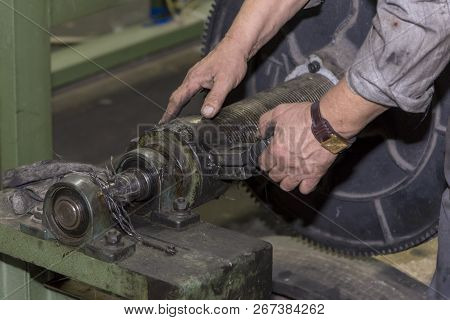 A Mechanic Repairs A Machine In A Factory.