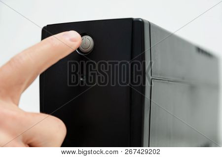 The Index Finger Is Pressing On The Start Button Of The Uninterrupted Power Supply.