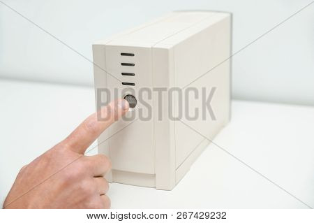 The Index Finger Is Pressing On The Start Button Of The Uninterrupted Power Supply.