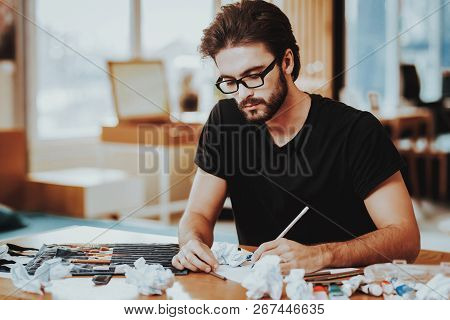 Talanted Freelance Male Artist Painting On Paper. Closeup Portrait Of Young Painter Sitting At Woode