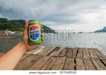 Portobelo, Panama  - May 28, 2016: Human Hand Holds A Can Of Panama Beer On A Wooden Pier In Portobe