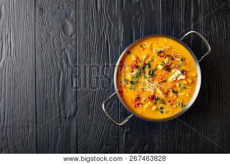 Overhead View Of Delicious Pumpkin Chicken Breast Savory Soup In Metal Casserole On Black Wooden Tab
