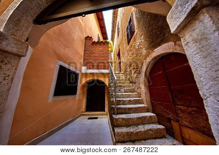 Lovran, Istria, Croatia. Vintage medieval buildings and houses at narrow lanes of old town. Stone stairs, wooden doors and windows. Decorative arch between brick walls.