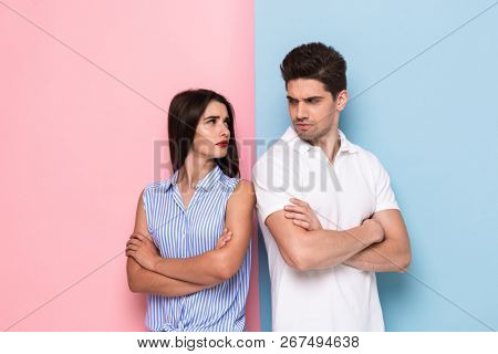 Photo of resentful man and woman in casual clothes standing with arms folded in quarrel isolated over colorful background