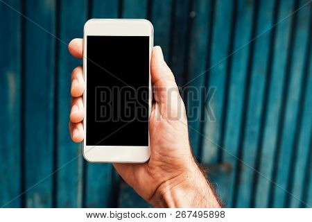 Hand With Smartphone Mock Up Screen In Urban Surrounding. Man Holding Mobile Phone Device With Blank