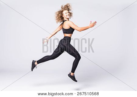 Full Length Picture Of Fitness Woman Jumping Over Gray Background