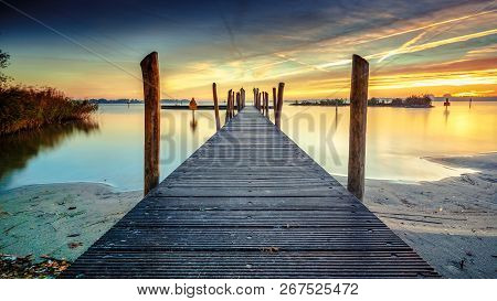 Beautiful Morning At The Lake On A Long Jetty With Wooden Planks, Morning Dew And A Colorful Sunrise