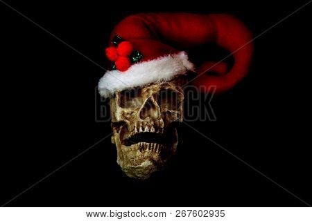 Evil Christmas Skull. Human Skull with a Santa Claus Hat. Isolated on black. Room for text. Evil Claus.