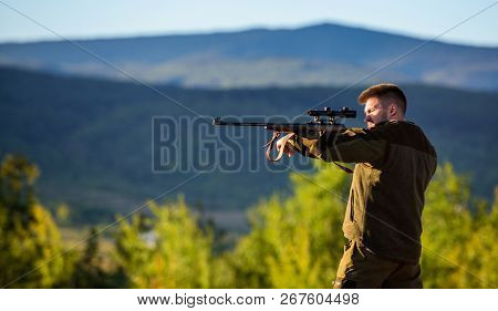 Hunter Khaki Clothes Ready To Hunt Hold Gun Mountains Background. Hunter With Rifle Looking For Anim
