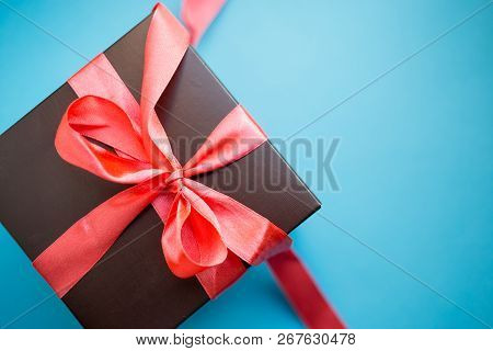 Brown Gift Box With Red Ribbon On Blue Background. Top View With Copy Space.