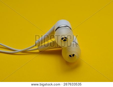 White Vacuum Headphones Close-up On A Yellow Background.
