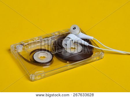 Retro Technology. Plastic Transparent Audio Cassette And White Vacuum Headphones On A Bright Yellow 