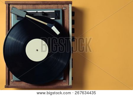 Vintage Vinyl Turntable With Vinyl Plate On A Yellow Pastel Background. Entertainment 70S. Listen To