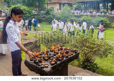 Kandy, Sri Lanka - July 19, 2016: White Clothed Buddhist Devotee Lights Candles At The Temple Of Sac