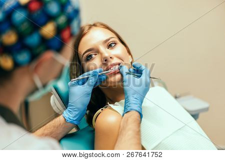 Dentist Examine Female Patient With Braces In Denal Office.